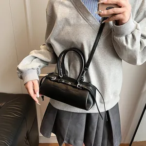 Detail of a black bucket bag with silver eyelets and adjustable strap on a model