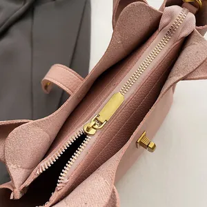 Détails du sac rose en cuir grainé avec fermeture éclair dorée et fermoir rotatif