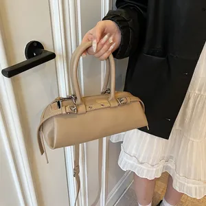 Detail of a retro beige baguette bag featuring metallic eyelets and dual handles