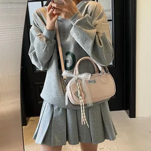 Detail of pink bowling bag with lace bow and woven charms shown in a mirror selfie