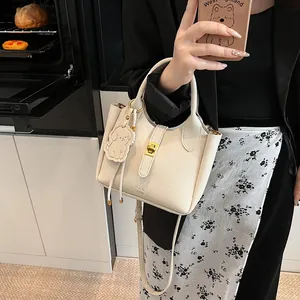 Détail du sac seau beige en cuir grainé avec fermoir doré et pendentif chien mignon