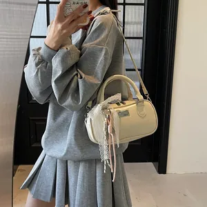 Detail of off-white bowling bag with lace trim and knot pendant shown in a mirror selfie