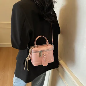 Rosafarbene Box-Handtasche aus Leder am Modell mit Metallbeschlägen und Reißverschluss
