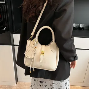 Détail du sac seau en cuir crème avec fermoir doré et pendentif petit chien