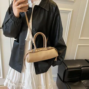 Detail view of beige leather baguette bag with curved handle and side buckle hardware