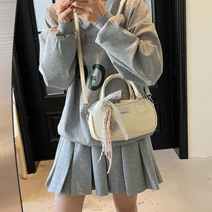 Detail view of a cream Boston bag with lace ribbons and adjustable crossbody strap