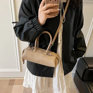 Detailed view of a beige baguette bag with metallic buckles and adjustable strap
