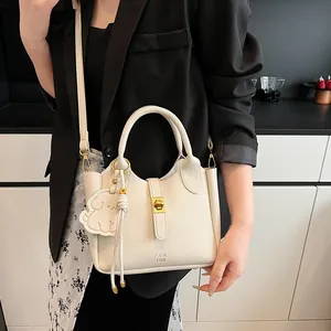 Détail du sac seau en cuir crème avec fermoir doré et pendentif chiot décoratif chic