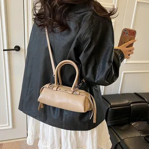 Detail of khaki faux leather baguette bag worn over the shoulder by a model