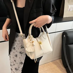 Détail du sac seau en cuir litchi blanc cassé avec fermoir doré et charme chien