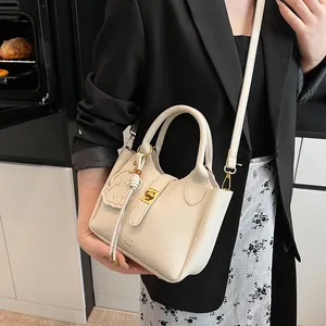 Détail d'un sac seau en cuir blanc crème avec fermoir en métal et charmant pendentif éléphant
