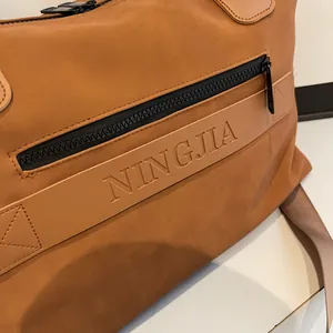Detailed close-up of brown travel bag with leather trim and NINGJIA embossed logo