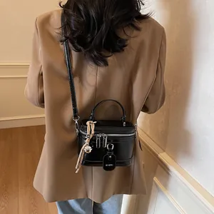 Rückansicht eines Models mit der schwarzen glänzenden Zylinderbox-Tasche und Silberdetails