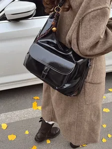 Vintage large capacity black crossbody bag with woven charm on an autumn street