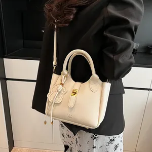 Détail du sac seau en cuir blanc crème avec fermoir doré et accessoire fleurie