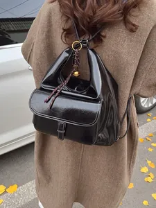 Glossy black multi-functional backpack with metallic buckle and golden bell charm