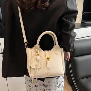 Détail du sac seau en cuir crème avec fermoir doré et accessoire pendentif éléphant