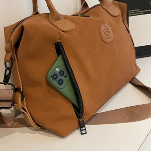 Close-up of side zipper pocket on brown travel bag with a green smartphone inside