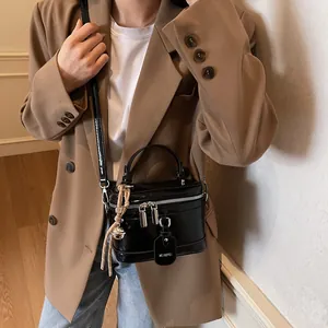 Hochwertige schwarze Lackleder-Box-Umhängetasche, kombiniert mit einem schicken Blazer.
