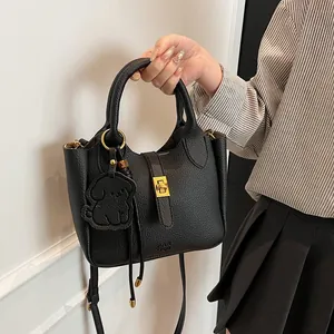 Détail du sac seau en cuir grainé noir avec fermoir doré et pendentif petit chien