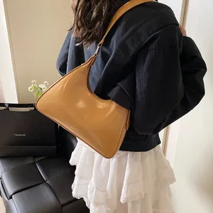 Detailed back view of a camel leather hobo bag worn on shoulder in a cozy indoor setting