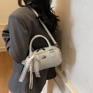 Close-up of light gray bowling bag featuring lace ribbon and silver logo plaque detail