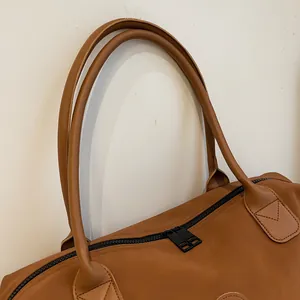 Detail of brown PU leather travel bag showing sturdy double zippers and reinforced handles