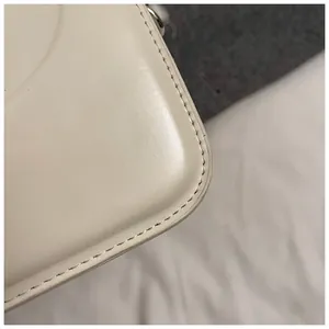 Vue détaillée des coins arrondis et des coutures de précision sur le sac à main en cuir crème