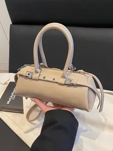 Retro beige cylinder baguette bag with silver buckles and dual top handles in a stylish pose