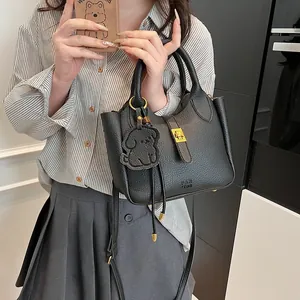 Détail du sac seau noir en cuir grainé avec fermoir doré et breloque chien mignonne