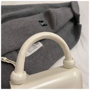 Détail du sac à main blanc crème avec boules décoratives et texture de cuir lisse