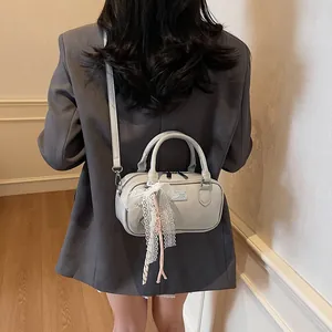 Back view of light grey bowling bag with lace bow and tassel on a female model