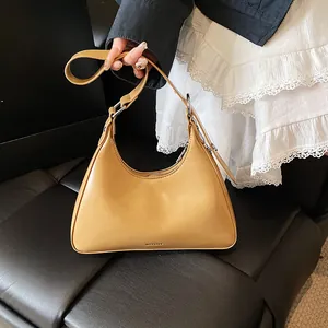 Detail shot of a ginger yellow hobo bag with sleek leather finish and silver hardware