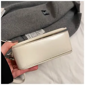 Gros plan détaillé du sac carré crème en cuir montrant les coutures et la texture fine