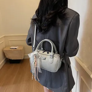 Detail showing greyish green mini Boston bag with delicate lace and woven charm detail