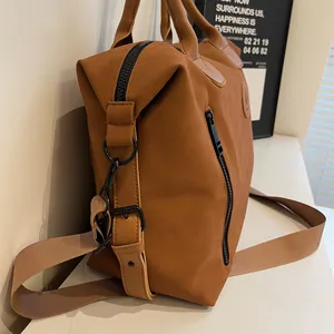 Detail view of large travel bag showing matte caramel brown fabric and black metal zippers