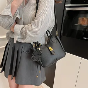 Gros plan d'un sac seau en cuir noir avec fermoir doré et pendentif en forme de chien