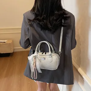 Fashionable light gray crossbody bag with lace bow and woven pendant on model