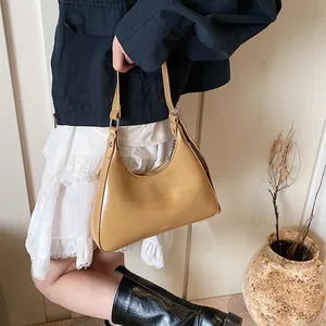 Detailed view of khaki leather crescent underarm bag with silver zipper and slim strap