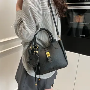 Détail du sac seau noir en cuir grainé avec breloque chien et fermoir doré tournant