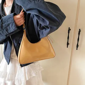 Detail view of a light brown crescent shoulder bag featuring NOT FILTER text and PU leather