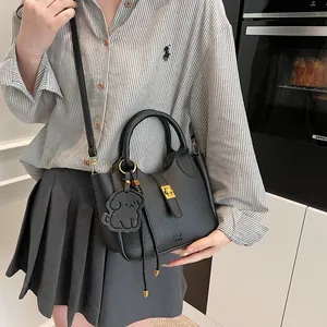 Détail du sac seau en cuir grainé noir avec fermoir doré et accessoire de chien mignon