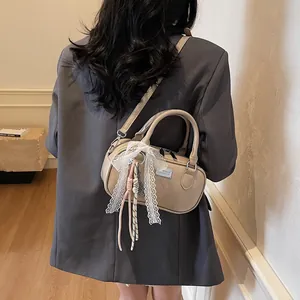 Detailed view of beige bowling bag with lace bow and tassel on a model's outfit