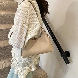 Close-up of beige crescent shoulder bag made of matte leather on a modern staircase