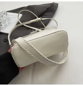 Detail of crocodile embossed cream handbag with unique hand-woven leather edge stitching