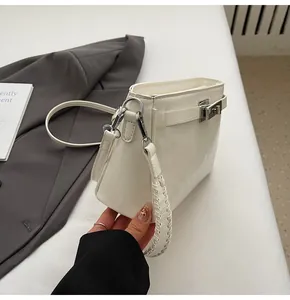 Close-up of white crocodile pattern handbag featuring a silver twist lock and woven handle