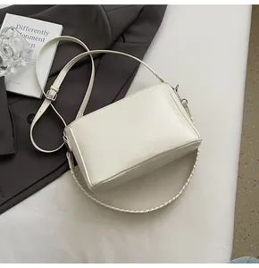 Detail of cream white textured faux leather bag with woven strap and adjustable metal buckle