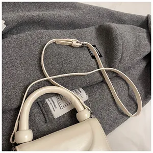 Gros plan du sac à main crème montrant la texture du cuir et les détails de la poignée
