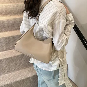 Detail of minimalist beige hobo bag with NO FILTER text shown on a model's shoulder