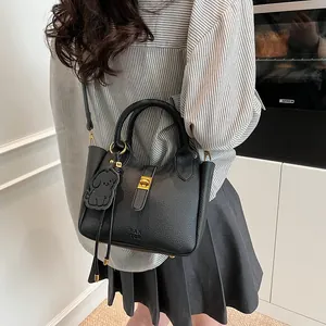 Sac seau en cuir noir à motif litchi avec poignée et boucle dorée sur mannequin